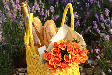 Canvas Print - Yellow wicker bag with beautiful roses, bottle of wine and baguettes near lavender flowers outdoors