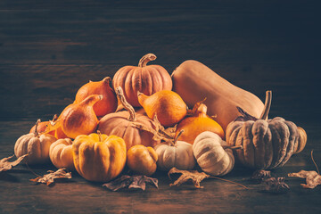 Wall Mural - Assortment of pumpkins with autumn leaves on wooden background