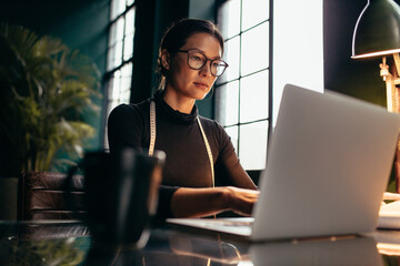 Female fashion designer working on laptop in studio