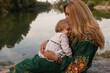 © rubchikova - A young mother and daughter are sitting near the river