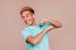 © carlesmiro - Young happy relaxed black boy dancing against beige background, having fun on party. Joyful man with curly afro hair listening music in wireless airpods earphones.
