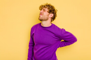 Wall Mural - Young caucasian man isolated on yellow background suffering a back pain.