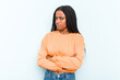 Young African American woman with braids hair isolated on blue background frowning face in displeasure, keeps arms folded.