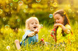 © Angelov - Two cheerful cute girls are playing outdoors with huge soap bubbles