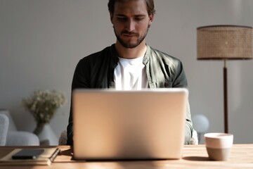 Wall Mural - Male remote working from home and having work confrence video call. Freelancer working on laptop at home office.