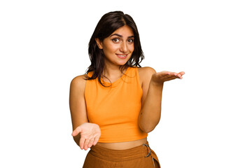 young indian woman isolated on green chroma background makes scale with arms, feels happy and confid