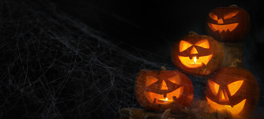 Wall Mural - Scary Halloween celebration holiday background banner panorama - Spooky carved pumpkins and dust in the dark black night