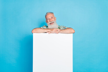 Wall Mural - Photo of cheerful aged person stand behind empty space ad blank isolated on blue color background