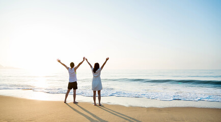 Wall Mural - Young couple embracing enjoying ocean on beach.