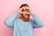 Portrait Of Cheerful Toothy Beaming Man With Red Hairdo Wear Blue Sweatshirt Hands Showing Eye In Heart Isolated On Pink Color Background