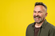Happy attractive handsome mature man with beard smiling isolated over yellow background. Active Positive middle-age person lifestyle concept.