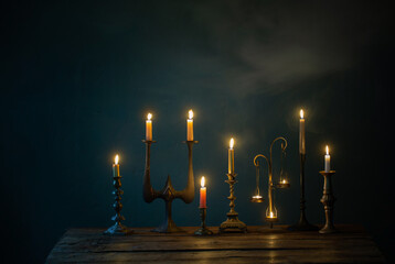 Wall Mural - burning candles in vintage candlesticks on dark background