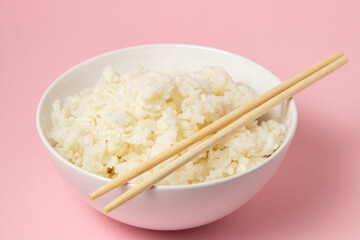 Wall Mural - A plate of boiled rice and chopsticks on a pink background. traditional asian food