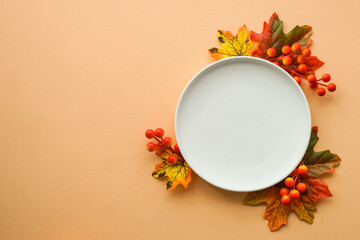 Wall Mural - Fall table setting. White plate and fall decorations at orange background. Flat lay image with copy space.