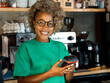 © gonzagon - Smiling african american female waitress in a pub with a dataphone in her hands. Small businesses, card payments