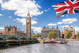 Fototapeta Big Ben - Big Ben with bridge over Thames and flag of England against blue sky in London, England, UK