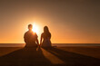 © kieferpix - Couple holding hands at sunset facing the ocean sunset. . Love and relationships concept.
