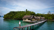 © Scopio - Man standing on wooden dock on body of water near wooden huts