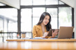 © David - Asian businesswoman working in the  workplace Office, Her is using touchpad while reading an e-mail on laptop and taking notes on the paper, accounting, tax, Financial, Business concept