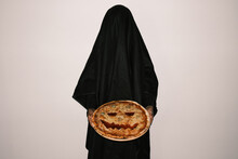 Horizontal Studio Shot Of Unrecognizable Young Woman Wearing Black Ghost Costume Demonstrating Pizza With Jack O Lantern Face Carved For Halloween Party