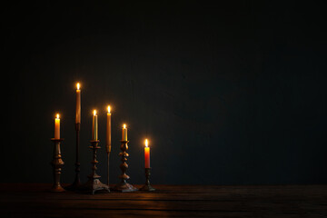 burning candles in vintage candlesticks on dark background