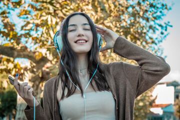 Wall Mural - relaxed happy girl with headphones outside in autumn