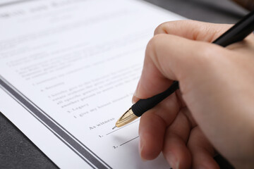 Poster - Woman signing last will and testament at grey table, closeup