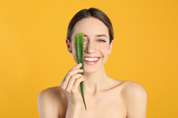 Canvas Print - Happy young woman with aloe leaf on yellow background