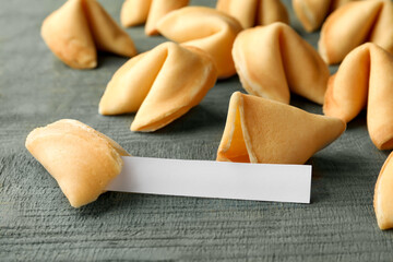 Tasty fortune cookies and paper with prediction on blue wooden table, space for text