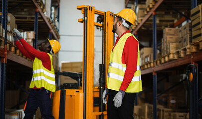 Wall Mural - Industrial workers loading delivery box inside warehouse store - Focus on right man hardhat