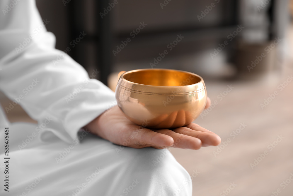 Man with Tibetan singing bowl meditating at home, closeup