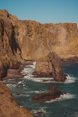 Vertical shot of a blue sea against a rocky coastline