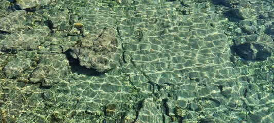 Sticker - Aerial panoramic shot of shallow sea coast with light green water and rocks under the sunlight