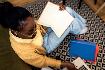 Wall Mural - Young African American female student studying at home using laptop.