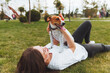 © inna717 - caucasian woman plays with her dog lying on the grass in the park. The concept of animals, friendship, people and love. a woman lies on the grass and plays with a jack russell terrier