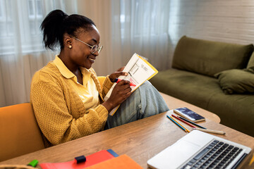 Wall Mural - Young African American female student studying at home using laptop.