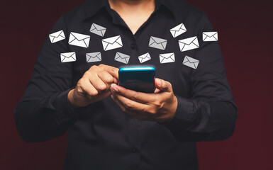 Wall Mural - bsinessman holding a smartphone receives a new message with email icons while standing in the office