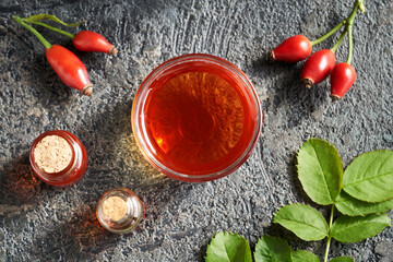 Red rosehip seed oil with fresh rose hips, top view