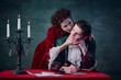Portrait of young man writing letter and woman in image of vampire biting his neck over dark green background
