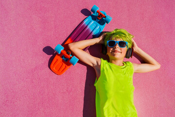 Child with green hair, skateboard portrait laying at skatepark