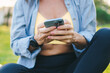 © Strelciuc - Closeup sporty woman hand typing on mobile phone smartphone while sitting on the grass. Active healthy sporty lifestyle. Checking fitness mobile application
