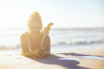 smiling elegant woman in white swimwear laying at beach