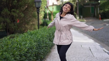 Wall Mural - A carefree happy Brazilian young woman pretending to fly with arms stretched in the air coming toward camera