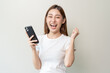 © Pormezz - Happy Asian woman holding a smartphone and winning the prize.