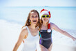 © Alliance - smiling mother and child in santa hat at beach having fun time