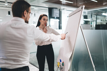 Wall Mural - Thoughtful colleagues analyzing diagrams on flip chart