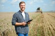 © Serhii - Happy farmer proudly standing in a field. Combine harvester driver going to crop rich wheat harvest. Agronomist wearing flannel shirt, looking at camera on a farmland
