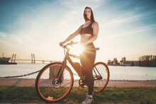 Athletic Girl Staying With Electric Bike Against Urban Seascape