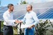 © Serhii - Two people having a shaking hands against solar panel after the conclusion of the agreement in the renewable energy