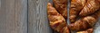 Fresh crispy french croissants on a wooden background. Traditional ruddy puff pastry (buns) for breakfast, delicious dessert, banner.